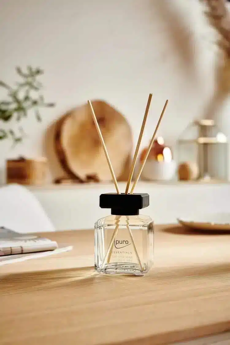 ipuro Essentials Cedar Wood Duftstäbchen in Glasfläschchen auf Holztisch mit warmem Hintergrund