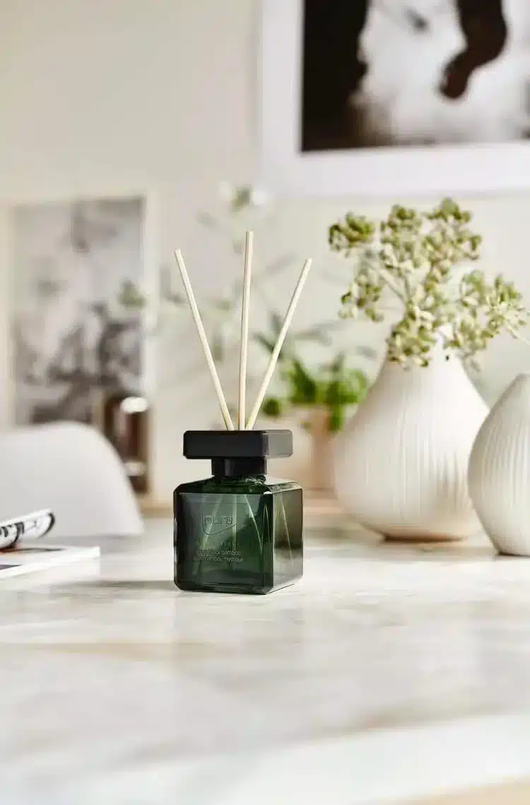 Ipuro Essentials Black Bamboo Duftstäbchen in dunkelgrünem Fläschchen auf Tisch mit Vase und Grün