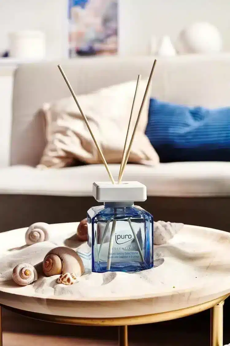 Ipuro Essentials Sunny Beachtime Duftstäbchen in blauer Flasche mit Muscheln auf rundem Tisch