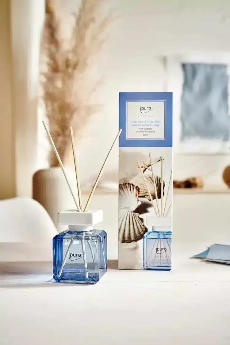 Ipuro Essentials Sunny Beachtime Duftstäbchen neben der Verpackung in einem hellen Wohnzimmer