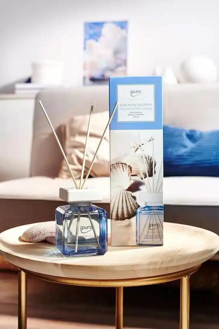 Ipuro Essentials Sunny Beachtime Duftstäbchen mit Verpackung auf einem runden Tisch beim Sofa